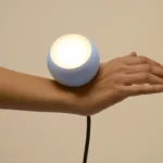 Grau Tischleuchte Falling in Love, Variante Light Blue, auf einer Hand