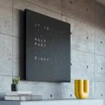 QLOCKTWO Earth 90 Black Pepper, Wanduhr über weißer Kommode