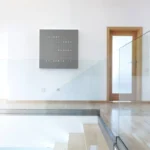 QLOCKTWO Earth 90 Grey Pepper, Wanduhr an weißer Wand